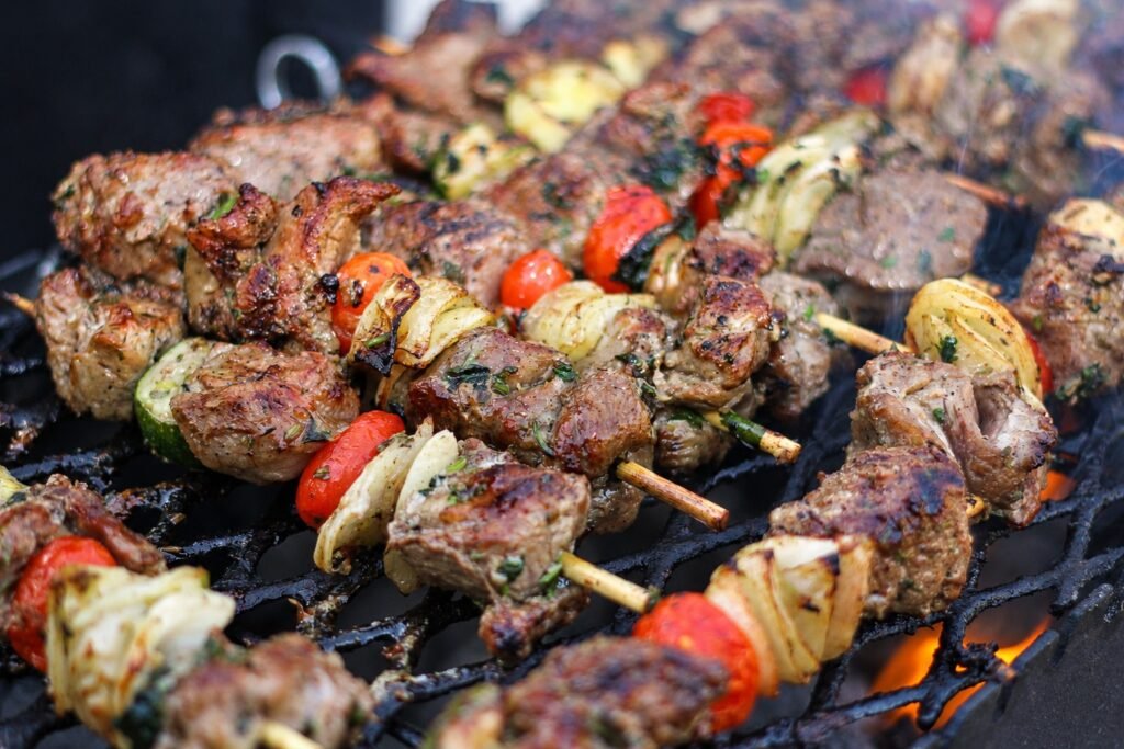 Close-up of grilled meat skewers with tomatoes and onions