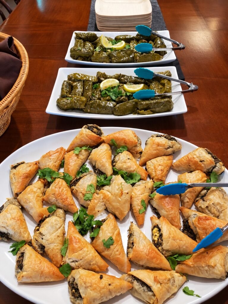 Savory pastries and stuffed grape leaves arranged on serving platters